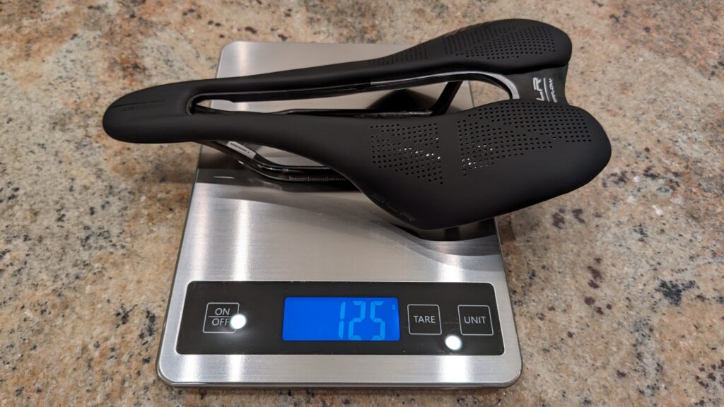 Photo of a Selle Italia SLK Boost Kit Carbonio Superflow bike saddle in size S3 shown on a scale showing a weight of 125 grams.