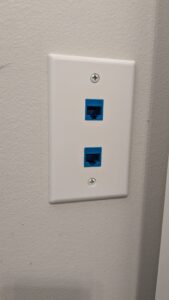 A photo of a wall plate with two keystone slots, each with a blue RJ-45 jack for connecting an ethernet cable.